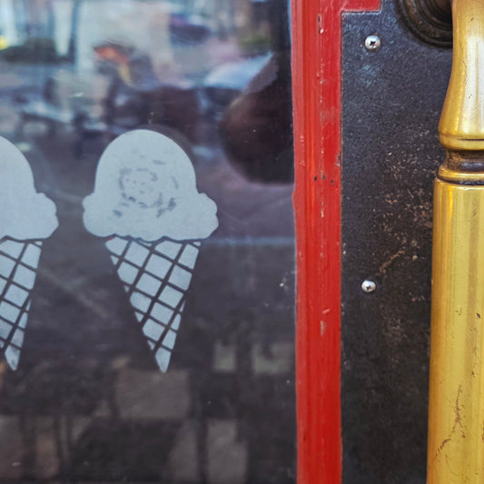 Vintage ice cream cone-themed door handle on a metal surface with reflections.
